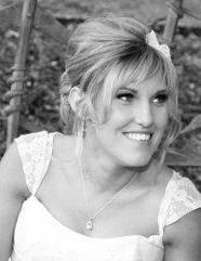 A bride smiling, hair pinned up with a flower