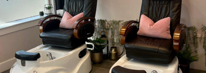 Two pedicure chairs with pink cushions and plants